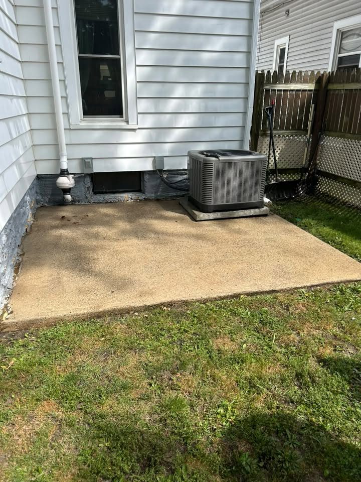 Cleaned concrete patio pad beside a house and air conditioning unit